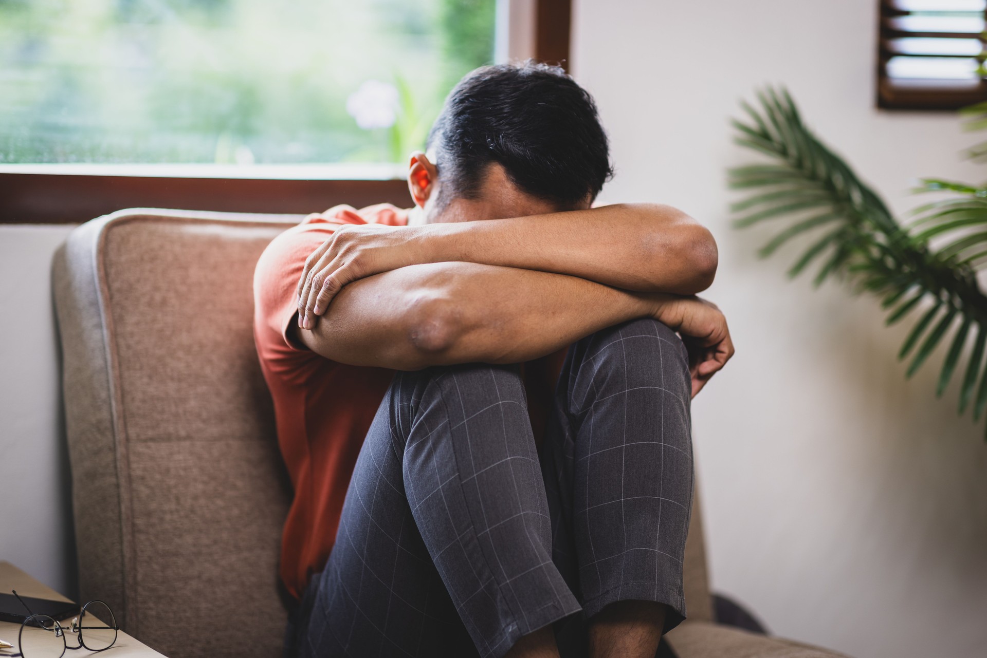 A man sitting on a sofa at home is sad, disappointed and upset.